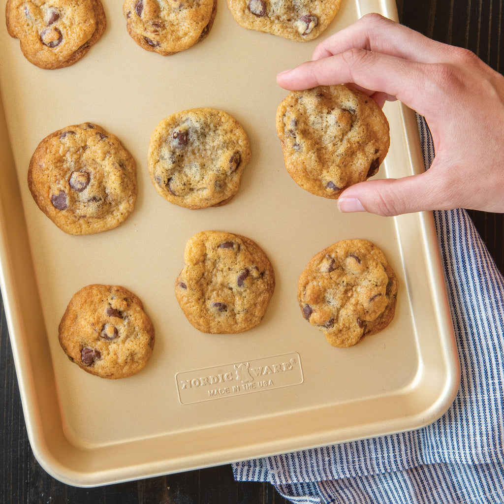 Nonstick quarter sheet pan with cookies baking, hand holding tray