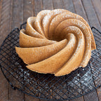 Bundt cake on cooling rack with ridged swirl grooves and powdered sugar