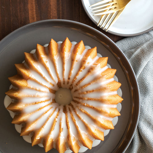 Bundt cake with fluted ridges and center hole, golden brown crust with light glaze