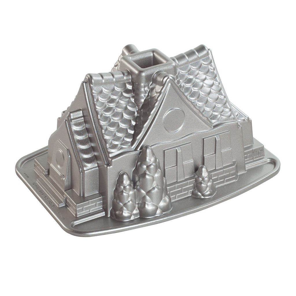 Silver metal gingerbread house bundt pan mold with detailed house design and base tray
