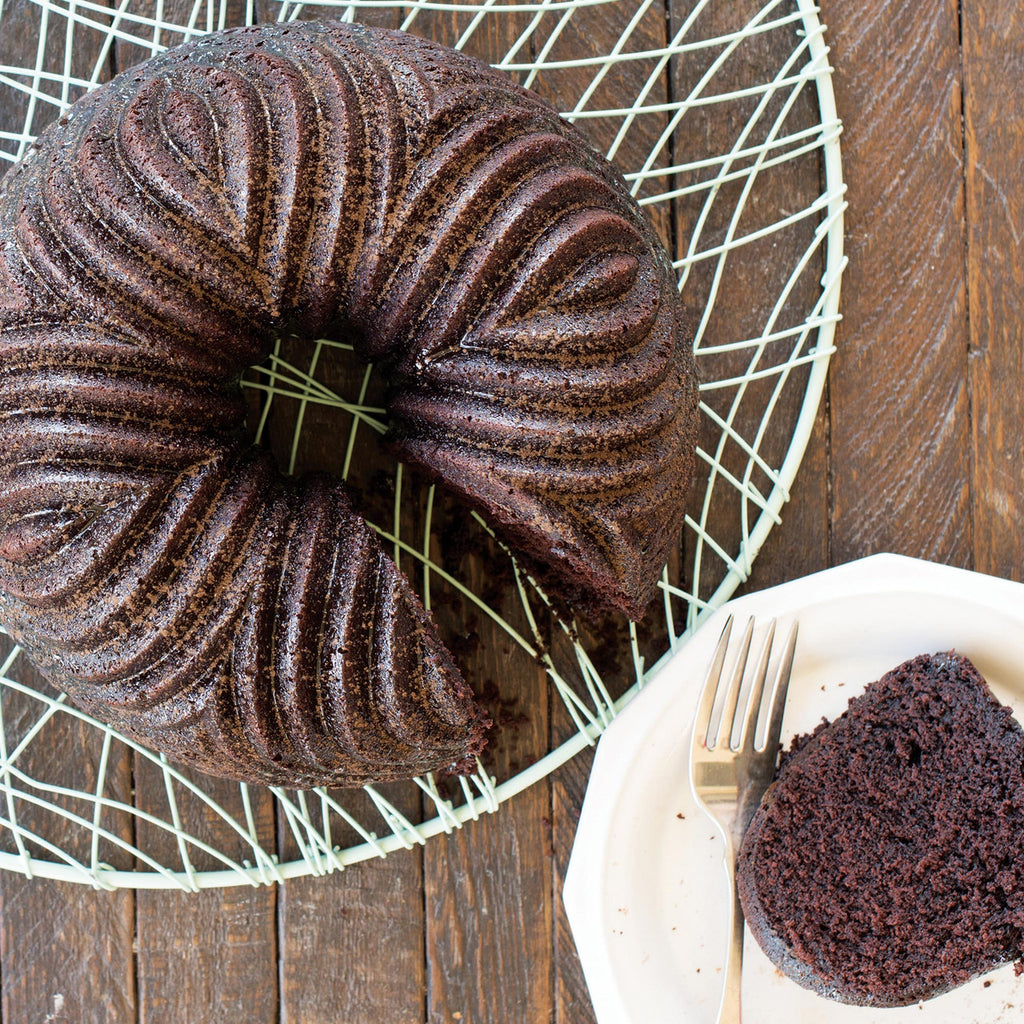 Bundt cake with dark chocolate ridged pattern, shown in the bundt pan on a rack.