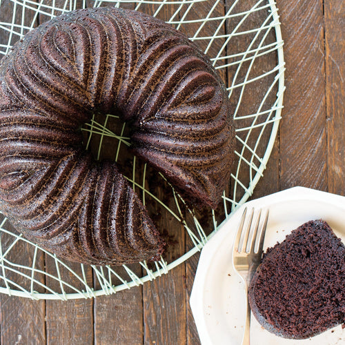 Bundt cake with dark chocolate ridged pattern, shown in the bundt pan on a rack.