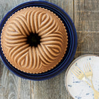 Bundt cake with golden-brown ridged design in a blue bundt pan.