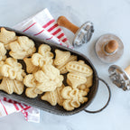 Holiday cookie stamp molds with wooden handles beside stamped cookies