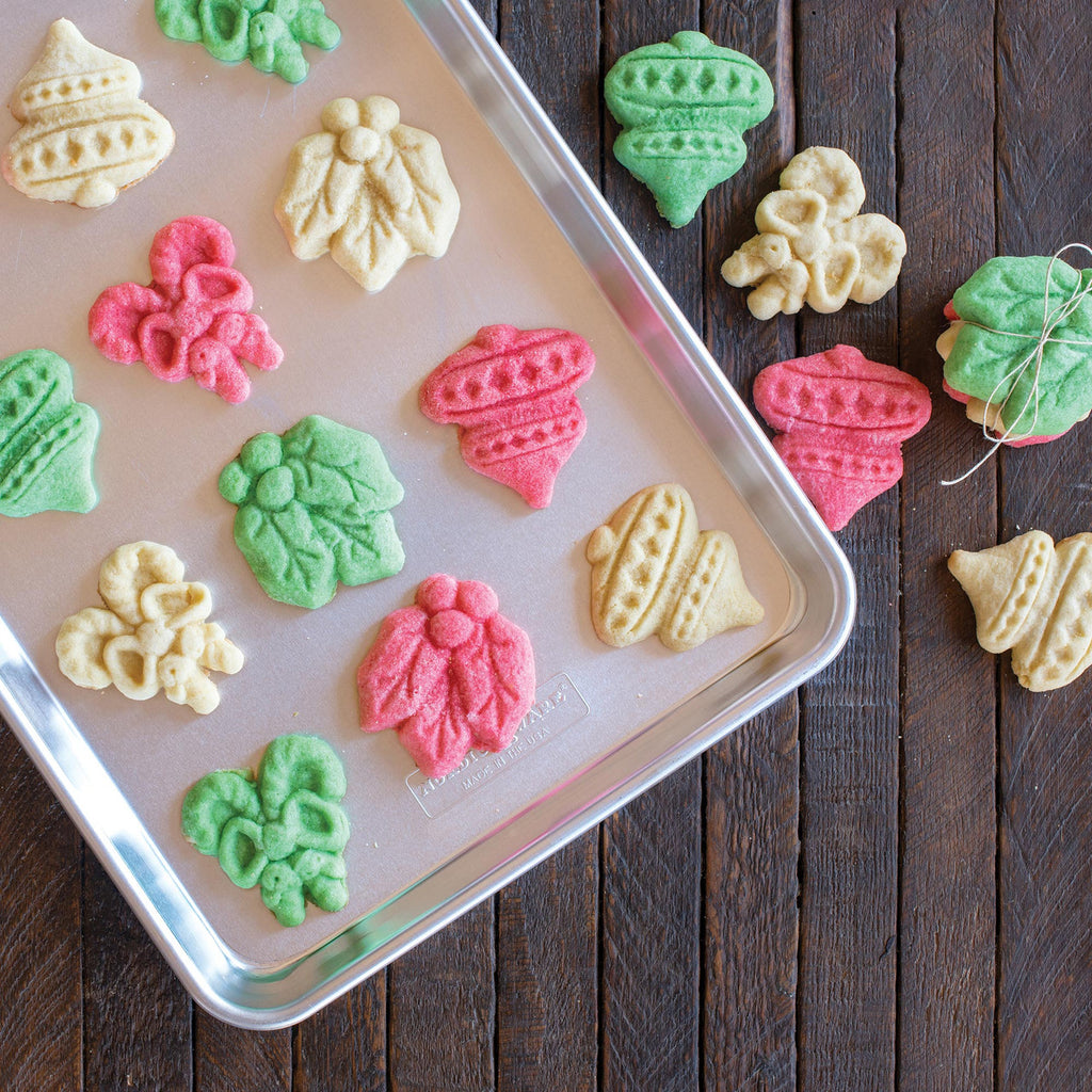 Assorted colorful stamped holiday cookies on a metal baking tray