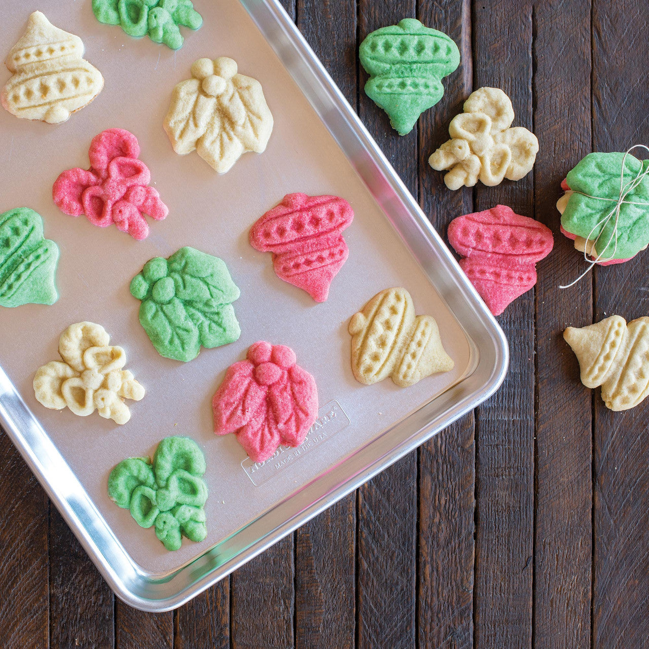 Assorted colorful stamped holiday cookies on a metal baking tray