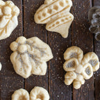 Stamped holiday cookies on wood with a silver cookie stamp mold nearby