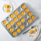 Brulee-style muffins in a silver 24-well muffin pan with serving plate nearby