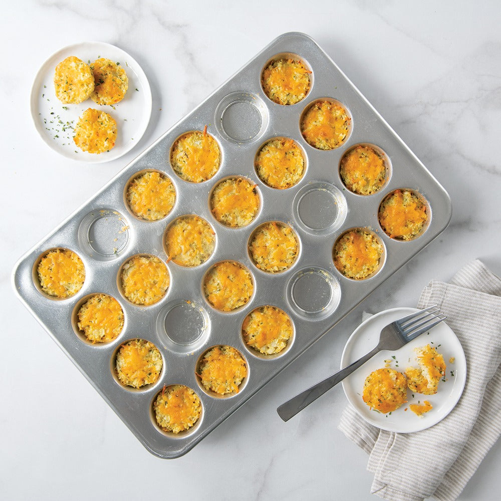 Brulee-style muffins in a silver 24-well muffin pan with serving plate nearby